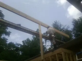 Carpenter setting a ridge beam over a new addition frame — Ice Dam Removal by Roofing Brothers in Green Ridge