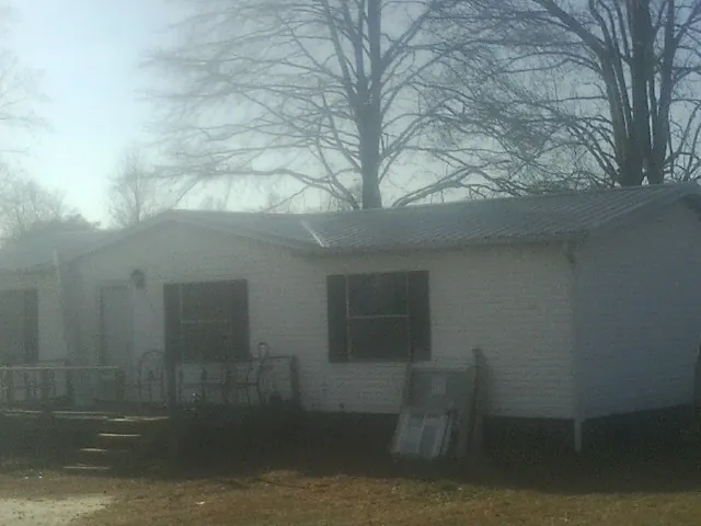 New metal roof on a white painted brick home on a foggy morning in Green Ridge