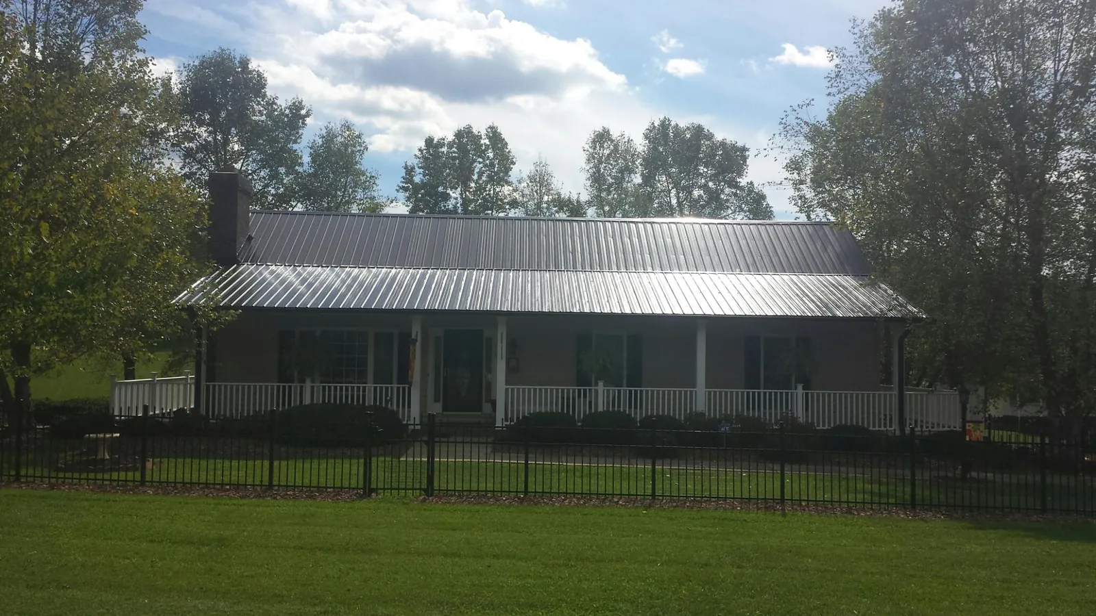 Gray metal roof on a brick ranch with a full width front porch — Gutter Guard Installation work by our crew in Green Ridge