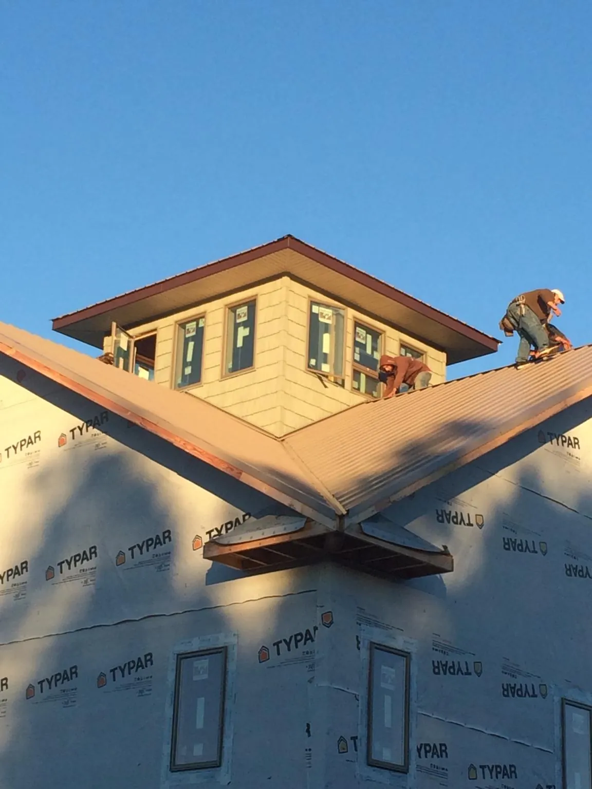 Roofers working around a rooftop cupola on a new metal roof at sunset — Roof Waterproofing in Green Ridge by Roofing Brothers